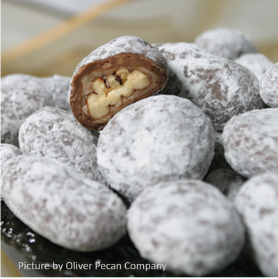 Chocolate toffee pecans covered in powdered sugar showing pecan meat inside
